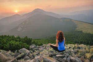 Woman feels freedom and enjoys the beautiful view in the mountains and looking on sunset